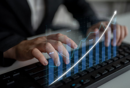 A business professional focusing on financial analysis using innovative graph projections while engaging with a modern keyboard in an office environment.の写真素材