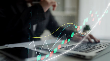 A business professional is focused on analyzing stock market trends using a laptop. Visualized...