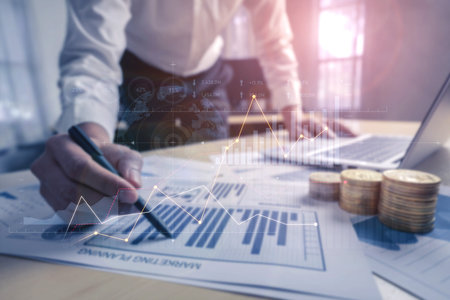 A business professional examines detailed financial data with charts and graphs in a modern office....
