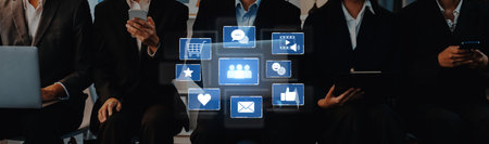 Business professionals in suits use their devices while interacting with digital icons representing...