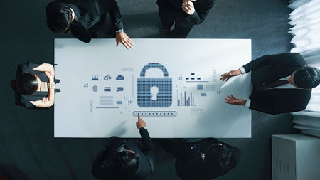 A business team collaborates around a table, focusing on cybersecurity strategies illustrated by...