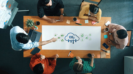 A diverse group of professionals collaborates on environmental sustainability strategies, focusing on carbon footprints, in a modern office setting filled with creativity. Rasterの写真素材