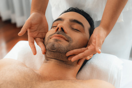 Caucasian man enjoying relaxing anti-stress head massage and pampering facial beauty skin recreation leisure in dayspa modern light ambient at luxury resort or hotel spa salon. Quiescentの写真素材