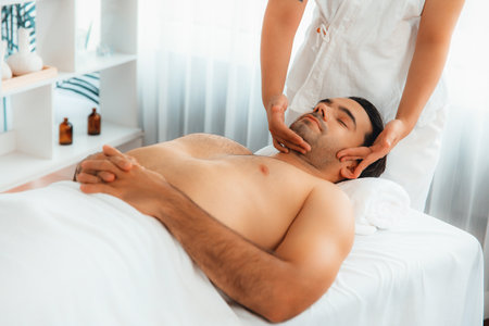 Caucasian man enjoying relaxing anti-stress head massage and pampering facial beauty skin recreation leisure in dayspa modern light ambient at luxury resort or hotel spa salon. Quiescentの写真素材