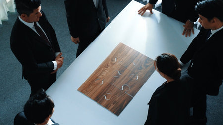 Top view of business people putting jigsaw together at meeting room. Professional marketing team standing at table while gathering puzzle piece. Show unity, cooperation and team working. Directorate.の写真素材