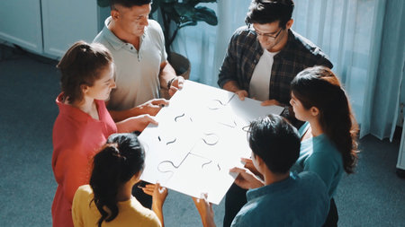 Top view of smart business people gathering jigsaw together at meeting. Aerial view of diverse team collect or put piece of jigsaw puzzle together and standing while wearing casual cloth. Symposium.の写真素材