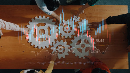 A group of professionals collaborates around a table featuring gears and stock market data visualization, emphasizing teamwork, strategy, and growth in business settings. Rasterの写真素材