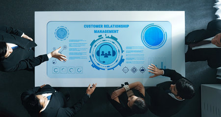 A diverse business team collaborates around a modern table with a digital interface, focusing on customer relationship management strategies and insights.の写真素材