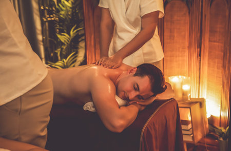 Caucasian man customer enjoying relaxing anti-stress spa massage and pampering with beauty skin recreation leisure in warm candle lighting ambient salon spa at luxury resort or hotel. Quiescentの写真素材