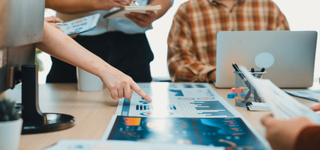 A group of professionals engages in a collaborative meeting, analyzing data charts and discussing...