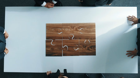 Top view of business people putting jigsaw together at meeting room. Professional marketing team standing at table while gathering puzzle piece. Show unity, cooperation and team working. Directorate.の写真素材