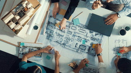 Top aerial view of project manager or civil engineer writing at blueprint and planning building design. Aerial view of architect working together at meeting table with document placed.の写真素材
