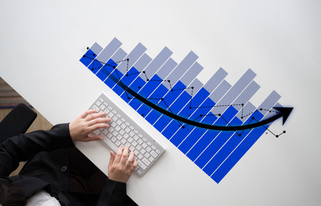 A business professional focuses on financial data analysis using a computer keyboard. A rising graph...