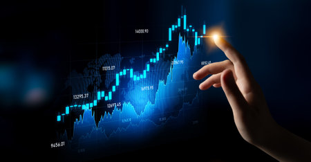 A hand interacts with a digital screen displaying glowing stock market graphics and analytics,...