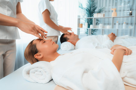 Caucasian couple enjoying relaxing anti-stress head massage and pampering facial beauty skin recreation leisure in dayspa modern light ambient at luxury resort or hotel spa salon. Quiescentの写真素材