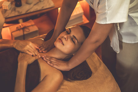 Caucasian woman customer enjoying relaxing anti-stress spa massage and pampering with beauty skin recreation leisure in warm candle lighting ambient salon spa at luxury resort or hotel. Quiescentの写真素材