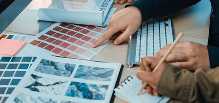 Two hands collaborate over colorful design samples, exploring textures and colors in a modern workspace, perfect for showcasing creativity and project development.の写真素材