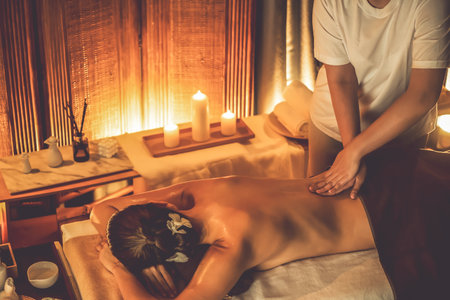 Caucasian woman customer enjoying relaxing anti-stress spa massage and pampering with beauty skin recreation leisure in warm candle lighting ambient salon spa at luxury resort or hotel. Quiescentの写真素材