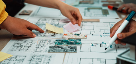 Hands reach for notes and sketches in a vibrant workspace, showcasing collaboration and creativity...