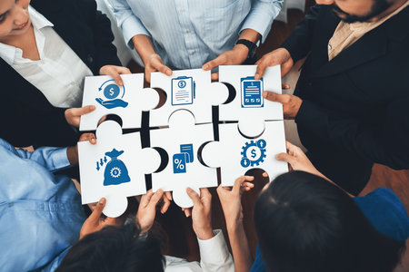 Diverse professionals collaborate using puzzle pieces to symbolize strategic reductions and financial insights, fostering teamwork and innovation in a modern workspace.の写真素材