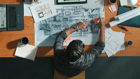Top down view of civil engineer handed document while looking at blueprint. Aerial view of architect team brainstorming idea and planning building design while sitting at table with plan. Symposium.の写真素材