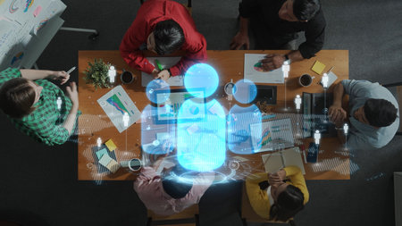 A diverse group of professionals collaborates during a brainstorming session at a modern workspace. A digital hologram enhances the creative environment, symbolizing innovative ideas. Rasterの写真素材
