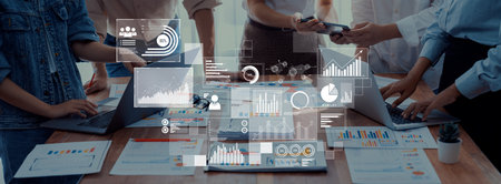 Team members collaborate in a modern office environment analyzing business data, utilizing digital...