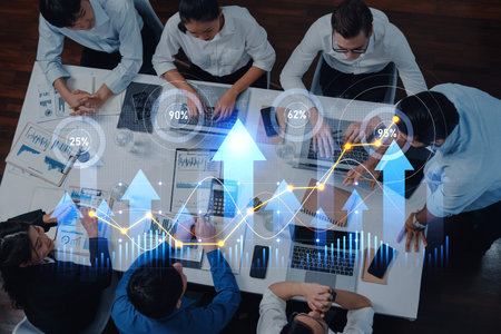 A diverse team engages in a strategic meeting with laptops and documents, analyzing data trends and sharing insights to drive business growth in a modern office.の写真素材