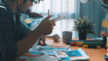 Top down view of smart designer helping manager choosing color from colored palettes. Aerial view of businessman working together and planning together while looking at logo from laptop. Symposium.の写真素材