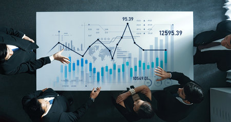 Team of professionals engaged in a business meeting discussing data analysis with financial graphs, showcasing collaboration and strategic decision-making in a corporate environment.の写真素材