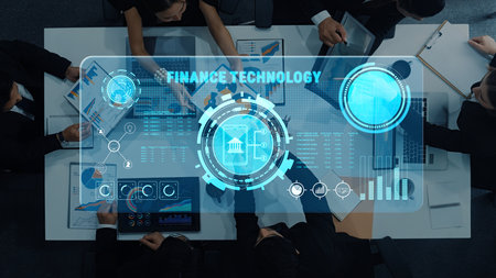 A business team engages in collaboration over a finance technology dashboard, using data visualizations and insights for strategic planning in a modern office setting.の写真素材