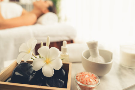 Aromatherapy massage on daylight ambiance or spa salon composition setup with focus decor and spa accessories on blur woman enjoying blissful aroma spa massage in resort or hotel background. Quiescentの写真素材