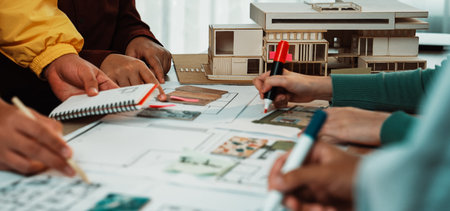 A creative team collaborates in an architectural studio, engaged in hands-on planning and sketching for innovative building designs, showcasing teamwork and professionalism.の写真素材