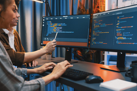 IT developers discussing with point to intelligent website development coder system running data online two screens information technology at neon light room at modern office. Infobahn.の写真素材