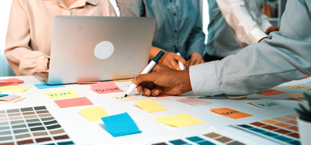 A dynamic scene depicting a creative team collaborating on project development with colorful sticky notes, a laptop, and effective communication in a modern office setting.の写真素材