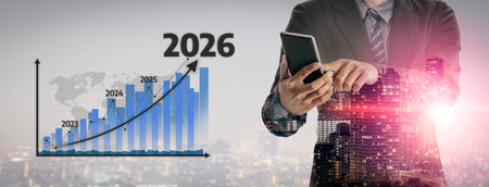 Businessman holds smartphone while analyzing financial graphs displaying growth trends forecasting...