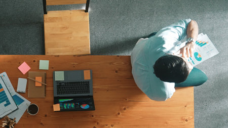 Top down view of businessman talking on phone with team while sitting on table. Smart manager speaking and calling with colleague about marketing strategy while looking at financial graph.の写真素材