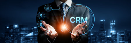 A business professional demonstrates the concept of customer relationship management (CRM) with digital icons in an urban night setting, showcasing modern technology and strategy.の写真素材