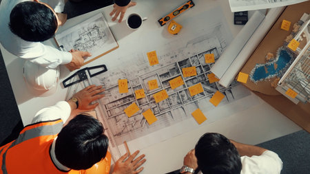 Top down view of skilled engineer team talking while looking at project plan. Aerial view of group of smart interior designer working together and planning for engineering construction.の写真素材
