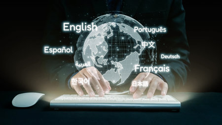 A person typing on a keyboard with a holographic globe displaying multiple languages, symbolizing global communication and digital interaction in a modern workspace.の写真素材