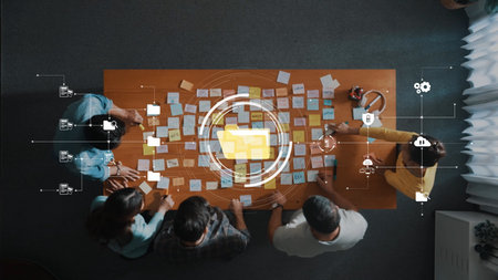 An overhead view of a collaborative meeting where professionals brainstorm ideas using sticky notes in a modern workspace setting, showcasing technology and teamwork. Rasterの写真素材