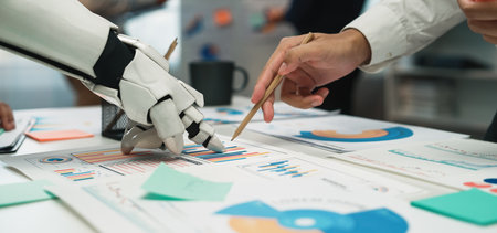 A modern office scene showcasing collaboration between a robotic hand and a human hand, analyzing various data charts and graphs for innovative business solutions.の写真素材