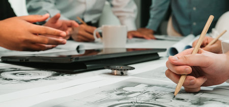 A dynamic brainstorming session featuring hands engaged in sketching and discussing designs with digital tools in a modern office setup, showcasing teamwork and creativity.の写真素材