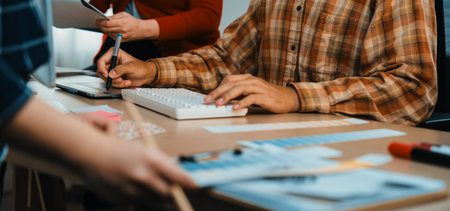 A dynamic creative office scene showcasing teamwork and collaboration. Hands engaged with a computer and paperwork highlight the essence of modern business creativity.の写真素材