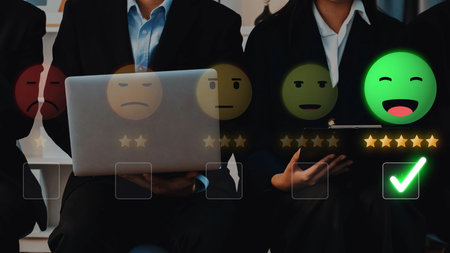 A group of business professionals engage in a feedback session, displaying various emotional responses with ratings, laptops, and tablets in a modern office setting. Rasterの写真素材
