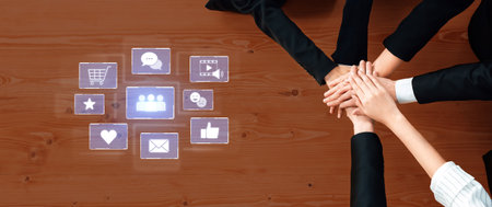 Diverse team members join hands on a wooden desk, symbolizing unity and collaboration while...