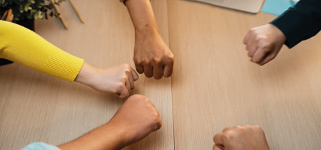 Vibrant hands of diverse individuals united in a gesture of collaboration and support in a modern office, symbolizing partnership and teamwork in a professional setting.の写真素材