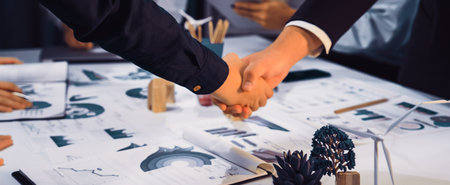 A business meeting captures the moment of a handshake between professionals, symbolizing agreement and collaboration over growth strategies displayed on charts.の写真素材