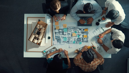 Top aerial view of project manager or civil engineer writing at blueprint and planning building design. Aerial view of architect working together at meeting table with document placed.の写真素材