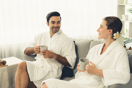 Beauty or body treatment spa salon vacation lifestyle concept with couple wearing bathrobe relaxing with drinks in luxurious hotel spa or resort room. Vacation and leisure relaxation. Quiescentの写真素材